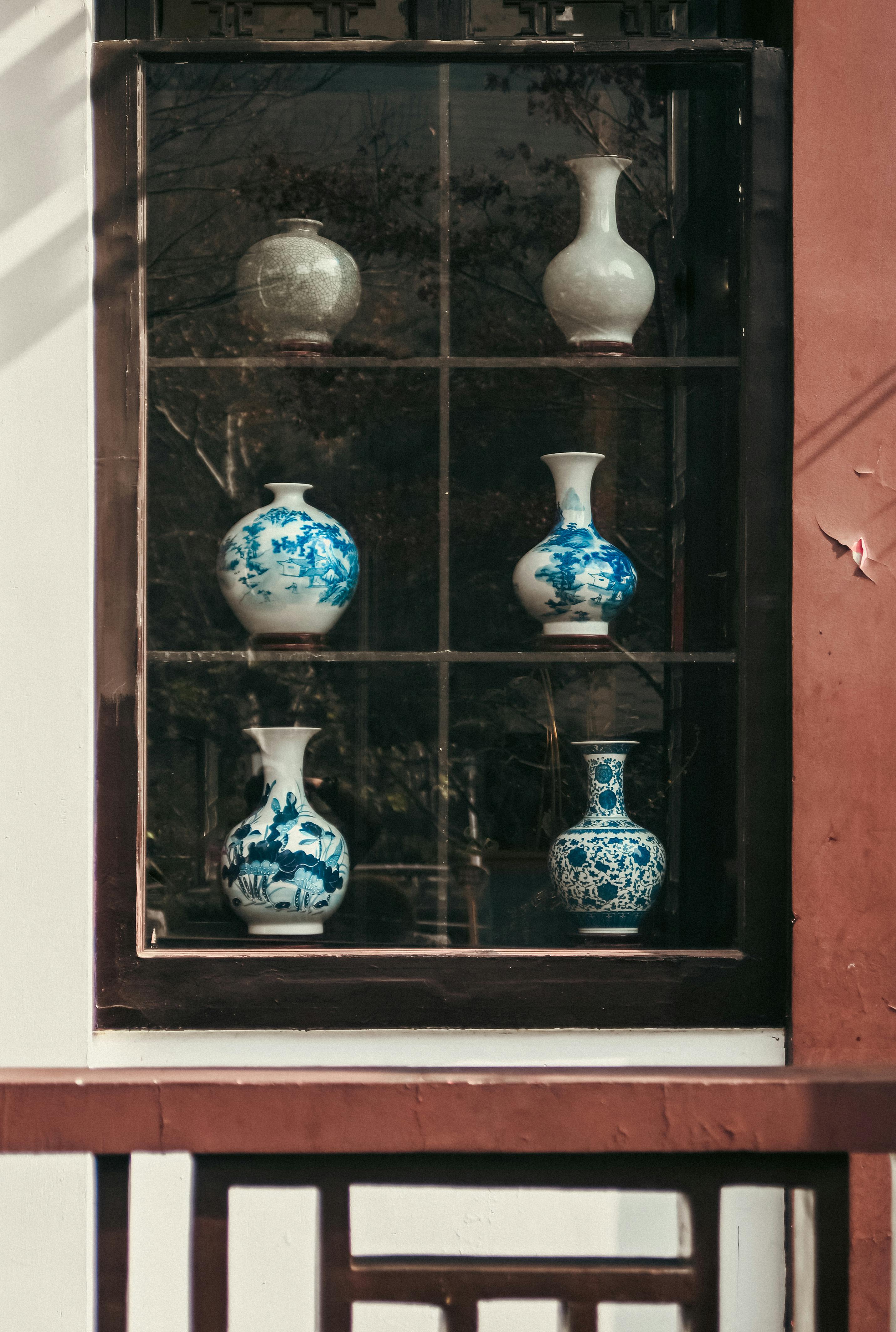 Blue and white porcelain vessels displayed in a window